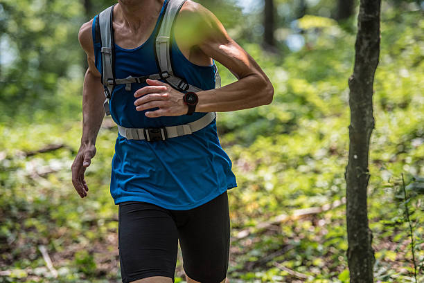 Mid section of man running in forest.