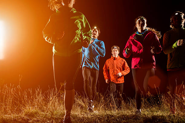 Young male and female joggers running on field at night