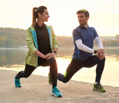 Young running couple warming up and stretching before running outdoors in the morning